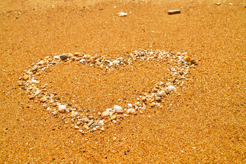 Heart from small stones and shells on beach