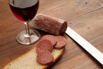 slice salami and bread with glass of red wine