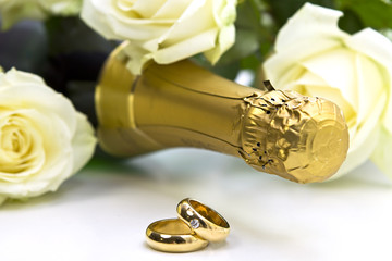 goldene Eheringe mit Champagner und Rosen