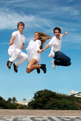 Group of friends in a jump against a city and the sky