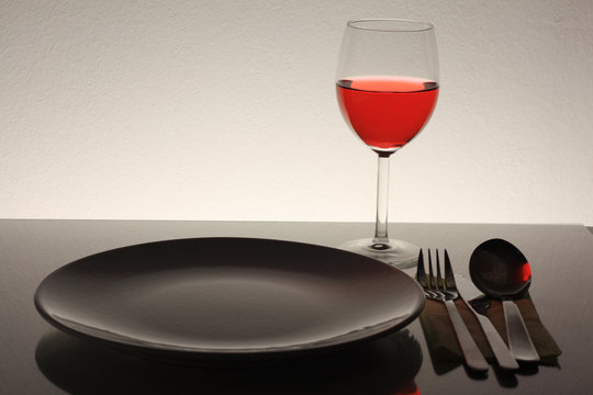 red wine and glass plate fork spoon and knife