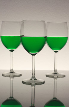 three win glasses with green wine
