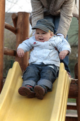 Glad boy sitting on top of slide in the park