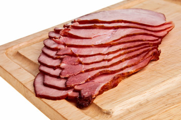 Smoked ham slices on wooden board.