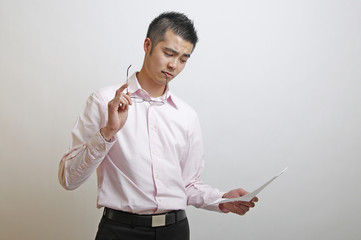 Asian office worker considering how to act on the information he