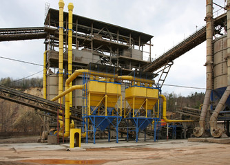 Stone quarry with silos, conveyor belts and piles of stones.