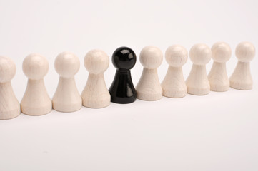 Schwarze Figure zwischen vielen weissen Figuren in einer Reihe