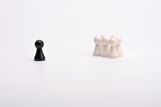 Schwarze Figur im Abstand zu einer Gruppe weisser Figuren