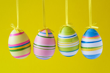 four colorful easter eggs isolated on yellow background