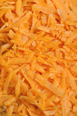 Freshly grated carrots background with selective focus