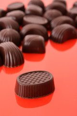 Assorted chocolate candies on red background