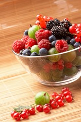 Fruit mix in the glass container, on a table from straw