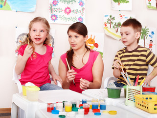Obraz na płótnie Canvas Children with teacher draw paints in play room. Preschool.
