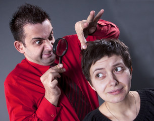 Man examining woman's hair with magnifying glass