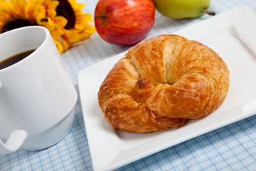 croissant with apples and coffee on a gingham tablecloth