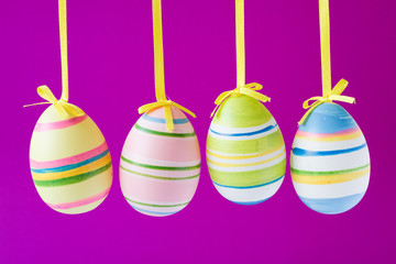four colorful easter eggs isolated on purple background