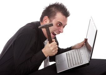Frustrated businessman destroying his PC with a hammer