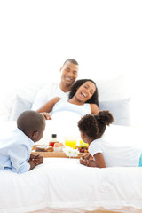 Obraz na płótnie Canvas Cheerful family having breakfast in the bedroom