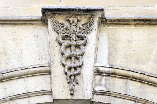 Caduc&eacute;e sculpt&eacute; sur une fa&ccedil;ade de pierre blanche.