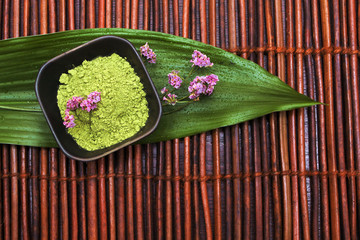 Green spa mud, violet flower and leaf on brown mat