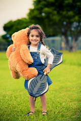 Cute girl standing in the grass holding teddy bear