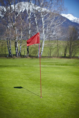 Obraz premium Red flag hole marker at the golf course