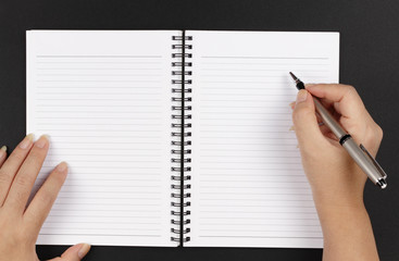 A pair of hands, a pen and a notebook