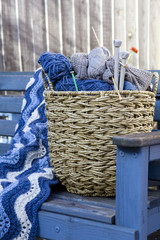 Blue wool and knitting needles in a wicker basket
