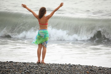 woman is staying near water on sea coast. wave in out of focus