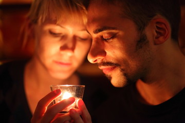 man and woman keeping glass candle. focus on man's left eye.