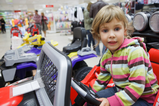 little girl in supermarket alone, chooses in department of toys