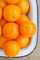 Oranges in a bowl on a hessian background