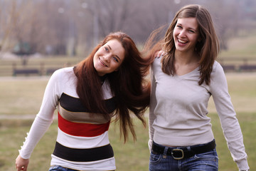 Obraz premium Two cheerful walking girls in the park