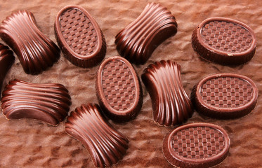 Assorted chocolate candies on brown background