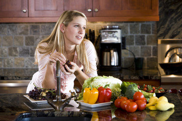 Teenage girl leaning on kitchen counter thinking