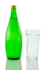 Bottle and glass of mineral water reflected on white background