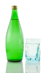 Bottle and glass of mineral water reflected on white background