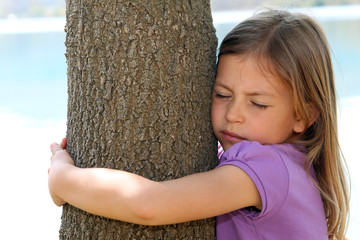 Cute young girl hugging a tree
