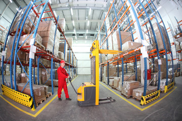 worker in red uniform at work in warehouse - fish eye lens - obrazy, fototapety, plakaty
