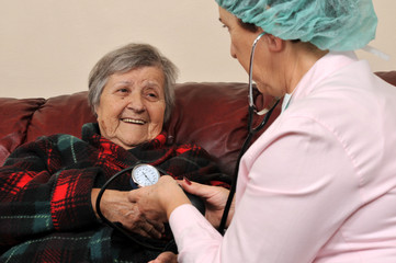 A nurse measuring senior patient's blood pressure.
