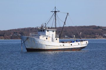 Old rusty fishing boat anchored in a protected harbor