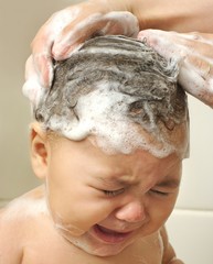 One-year-old baby girl washing hair crying