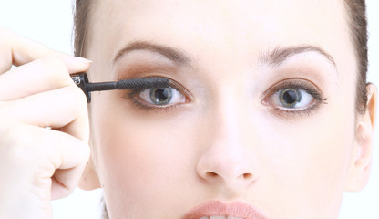 Portrait of pretty young woman applying mascara