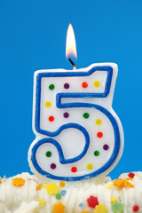 Number five birthday candle on blue background