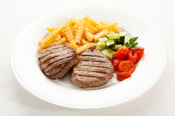 Grilled steaks with chips and vegetables