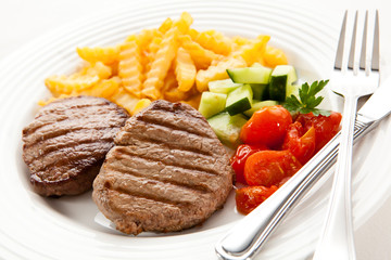 Grilled steaks with chips and vegetables