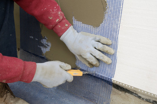 Worker hands cut mesh on styrofoam insulation