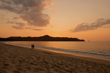 Romantic beach sunset young couple holding hands.