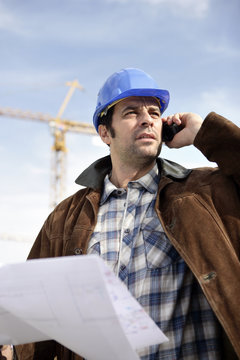 Portrait d'un ouvrier au téléphone portable un plan à la main