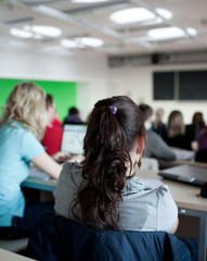 young pretty female college student sitting in a classroom full